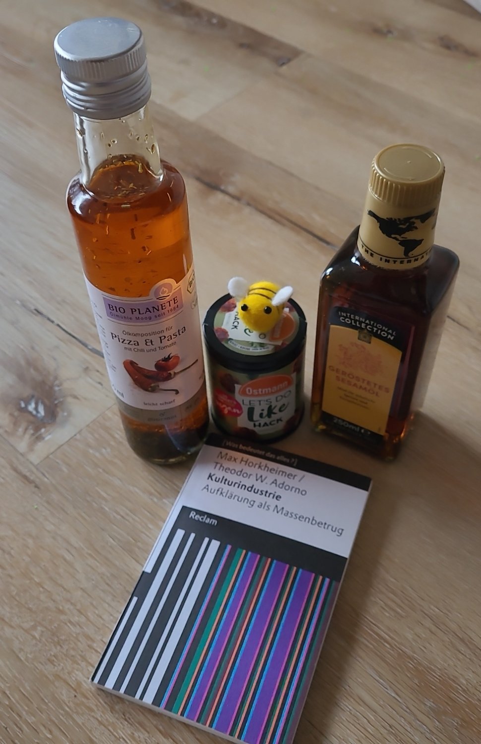 Der Inhalt des Wichtelpakets: eine Flasche Sesamöl, eine Flasche gewürztes Öl für Pizza und Pasta,  Gewürz für veganes Hack, das Buch "Kulturindustrie" von Theodor W. Adorno und ein gefilztes Bienchen