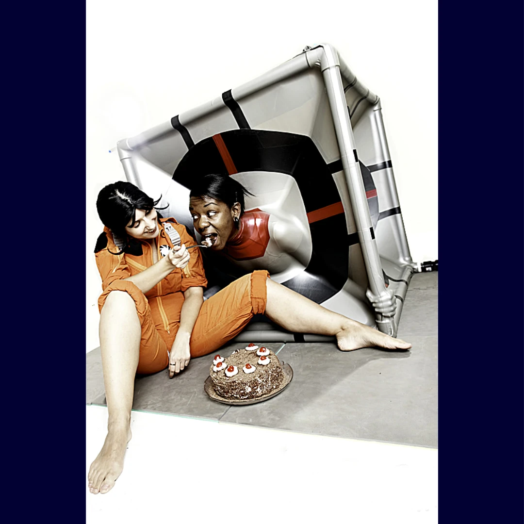 from the cube's product page someone dressed up as chell from portal feeding someone in a companion vac cube the portal cake