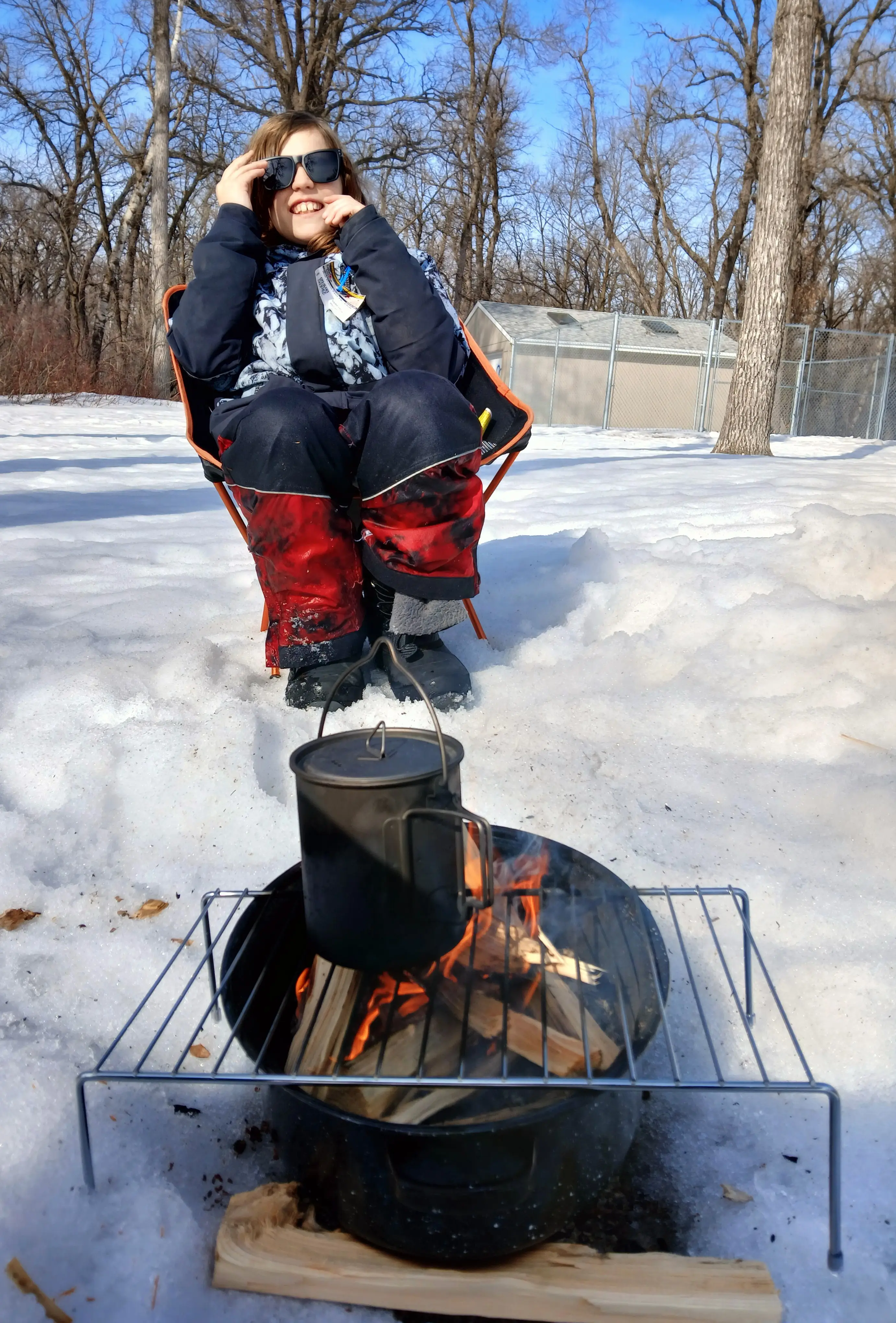 Child smiling sitting next to the camp fire