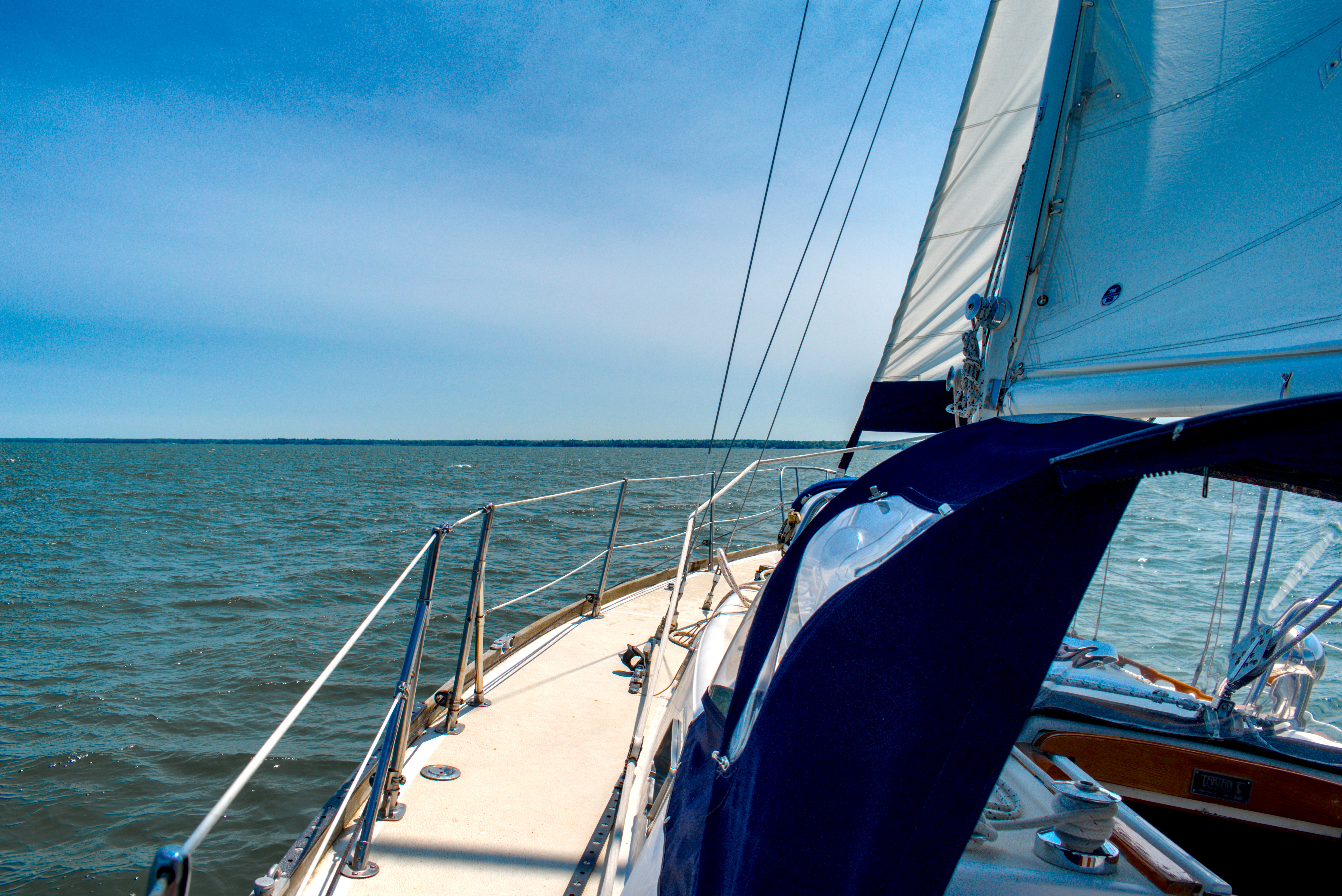 The view from the port side cockpit of asailboat under sail in Chequmegon Bay.