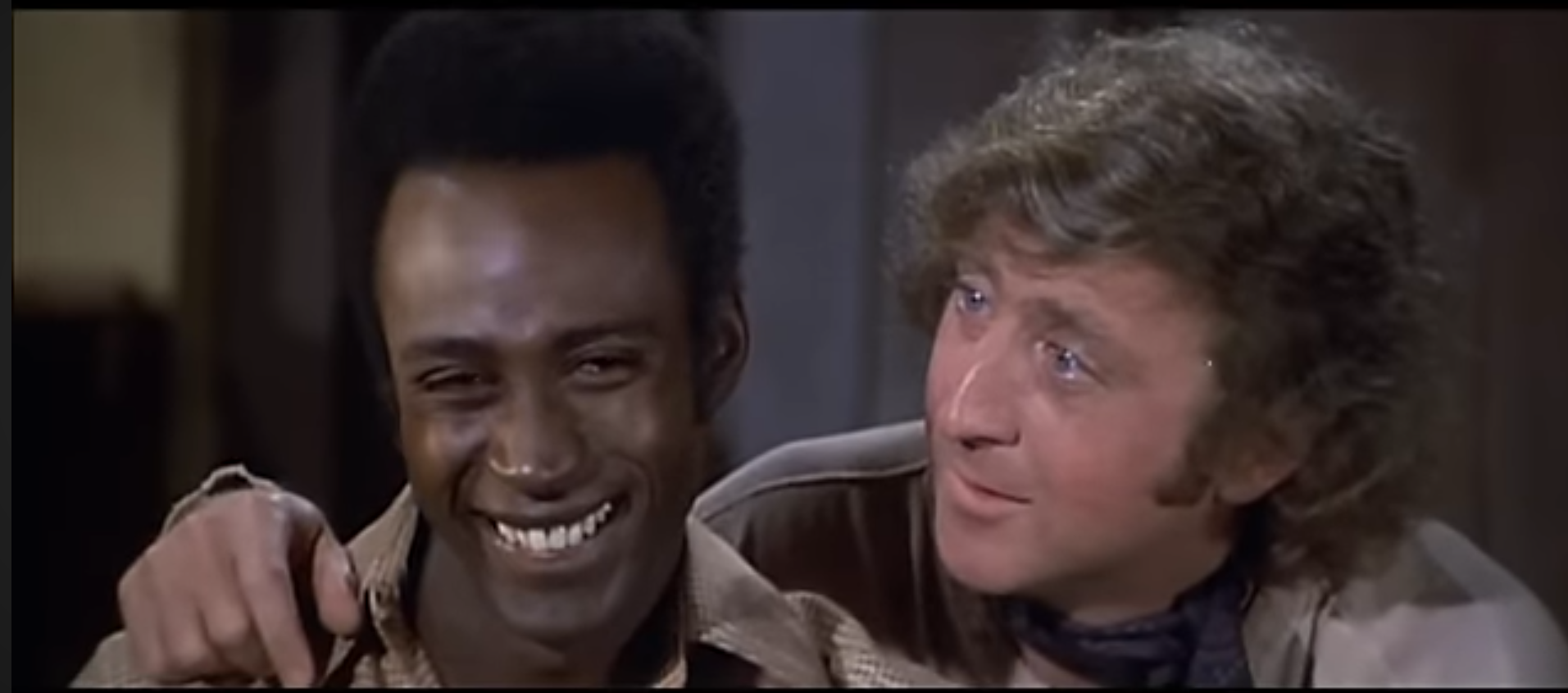 Screenshot from "Blazing Saddles" showing Cleavon Little cracking up laughing at what Gene Wilder just said to him.