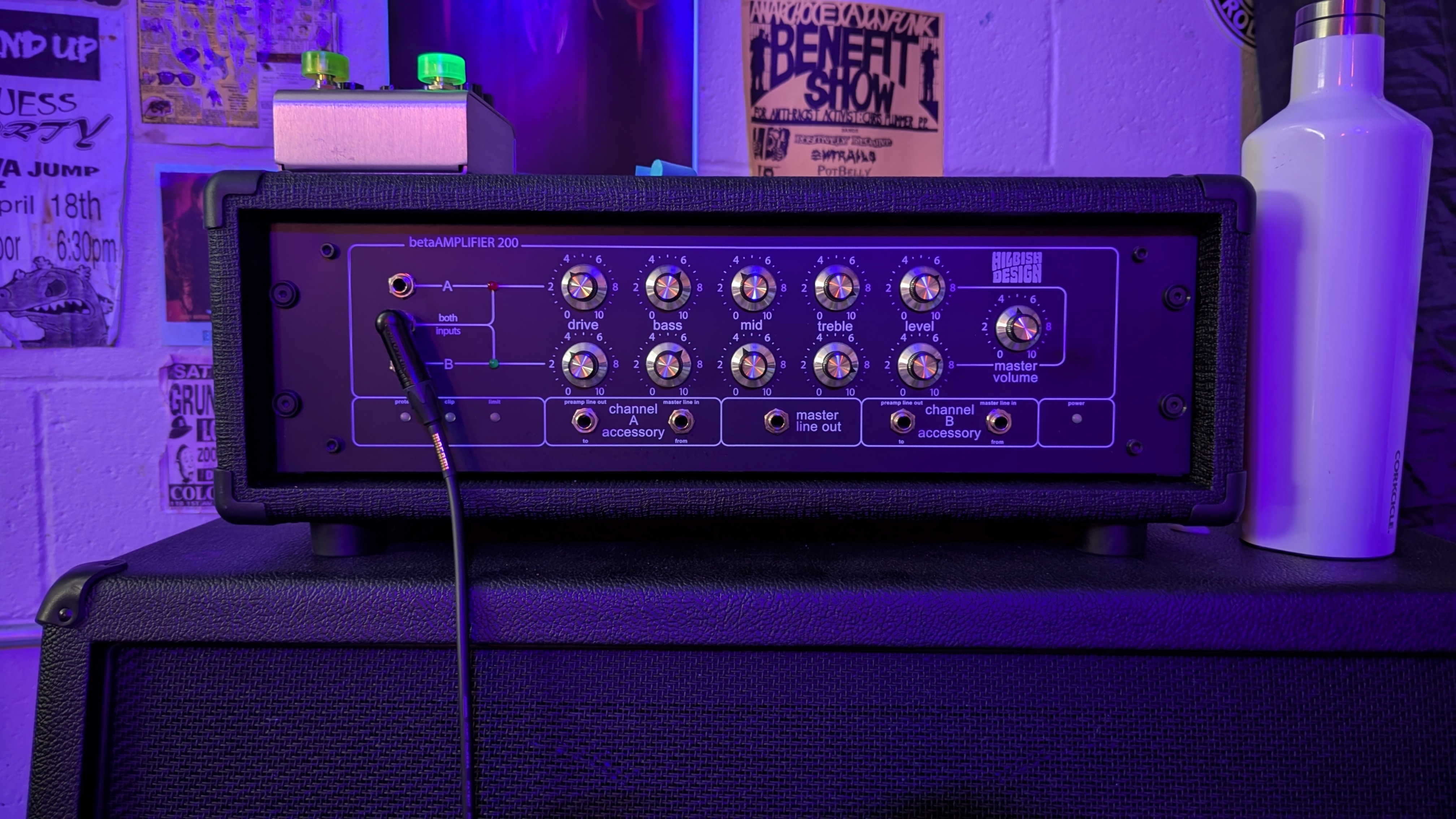 Guitar amplifier sitting on a cab with a pedal on top