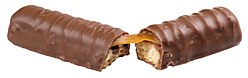 Twix candy bar slightly broken to reveal the caramel and cookie crisp inside that delicious chocolate coating.