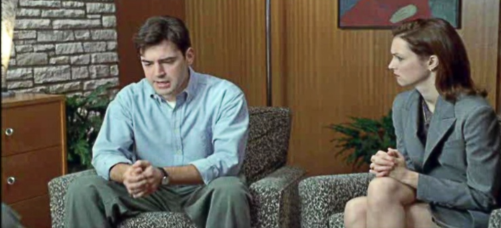 Still picture of the movie Office Space. Man with hands clasp and last on the right.