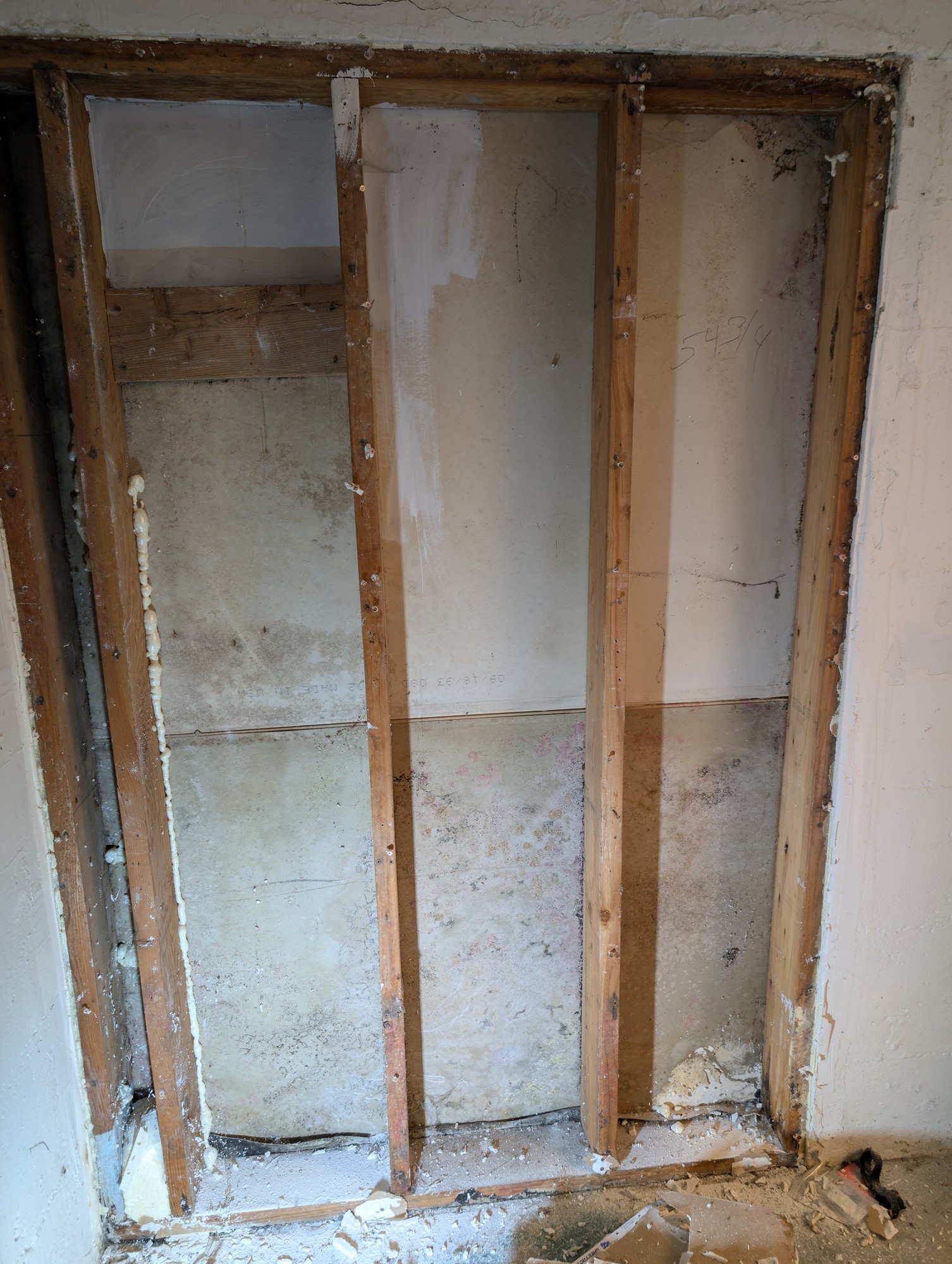Wall with exposed studs, showing damage and concrete on all 4 sides