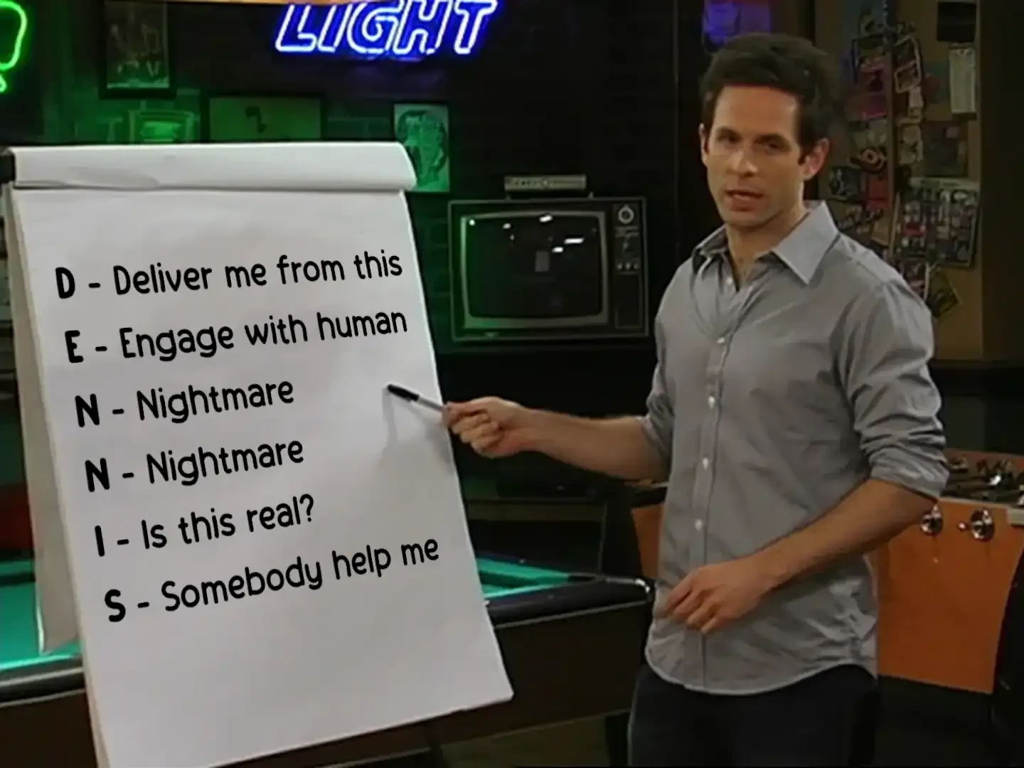 Dennis pointing at a posterboard that reads "D - Deliver me from this, E - Engage with human, N - Nightmare, N - Nightmare, I - Is this real?, S - Somebody help me"