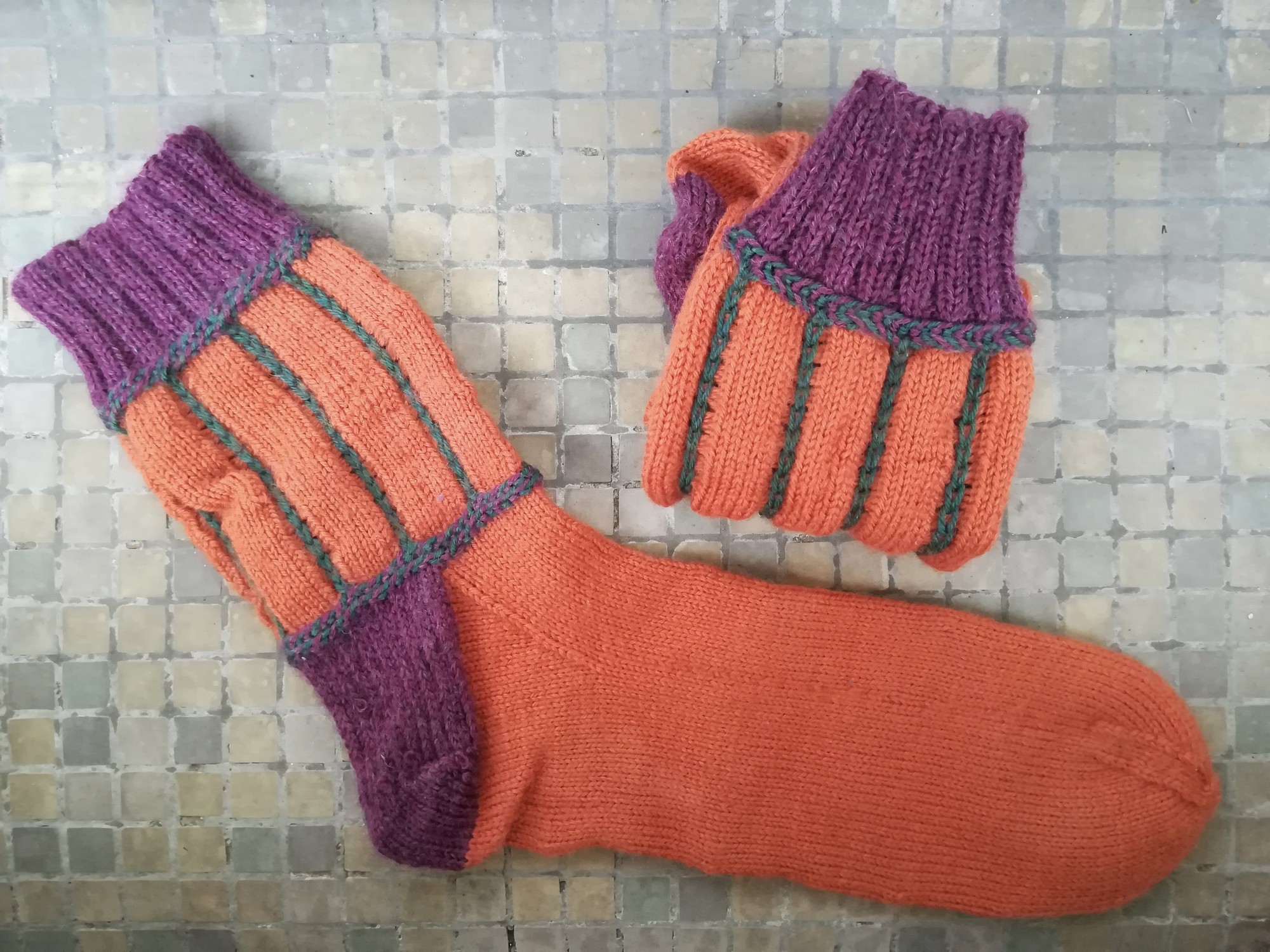 Photo d'une paire de chaussettes tricotées, de couleurs orange, violette et verte. 